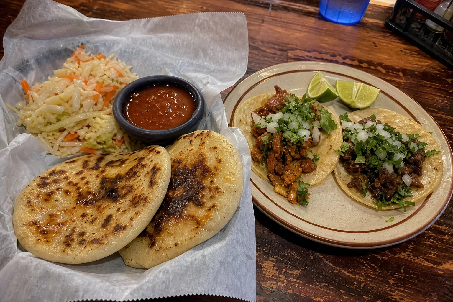 Pupusas with curtido salsa and tacos on a worn wood table